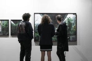 Trois visiteurs de dos regardent des photographies encadrées sur un stand de foire