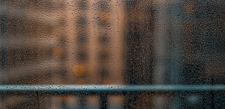 Gotas de água se acumulam em vidraça com prédios desfocados ao fundo. Umidade é um perigo para obras de arte porque favorece surgimento de fungos e mofo.