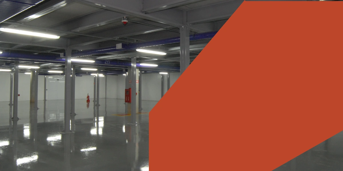 Salão de armazenagem vazio, com piso espelhado e iluminação em linha